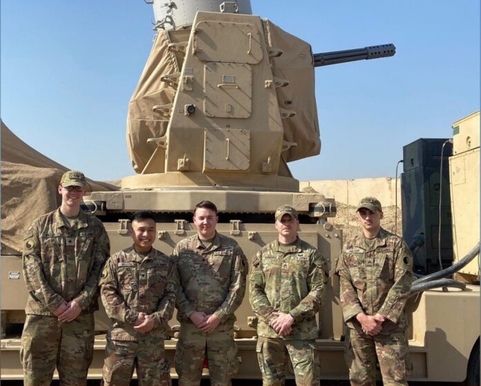 Matthew Wells (at left) and his unit in front of the C-RAM weapon system in Iraq. Photo courtesy of Matthew Wells.